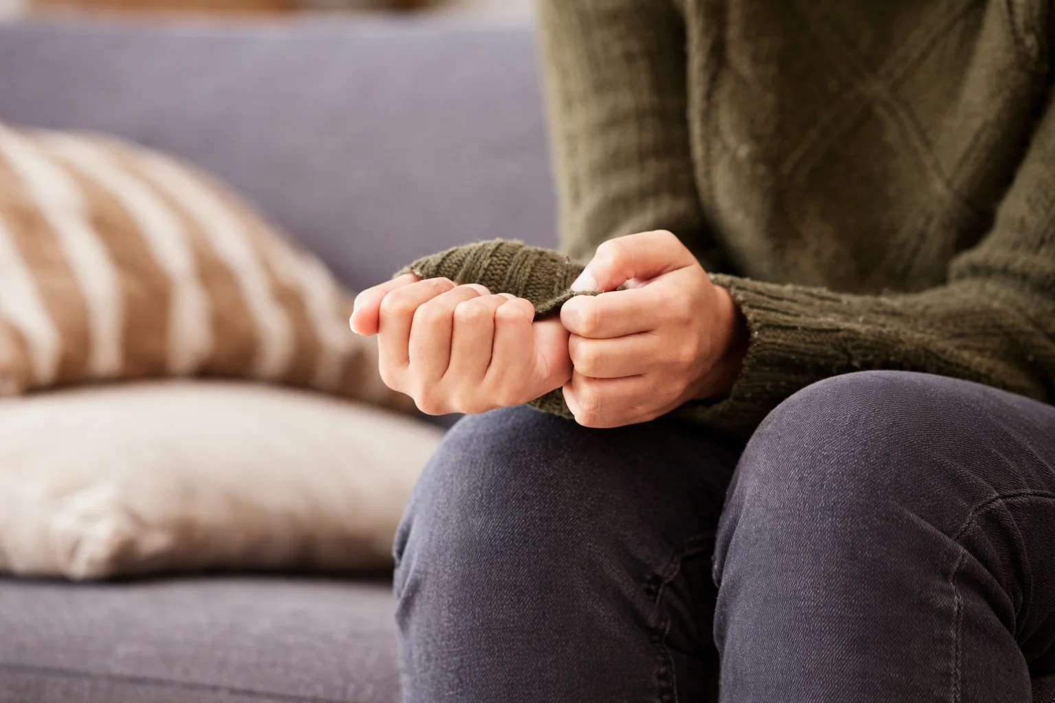 Anxiety shaking captured as a person grips their sweater cuff tightly